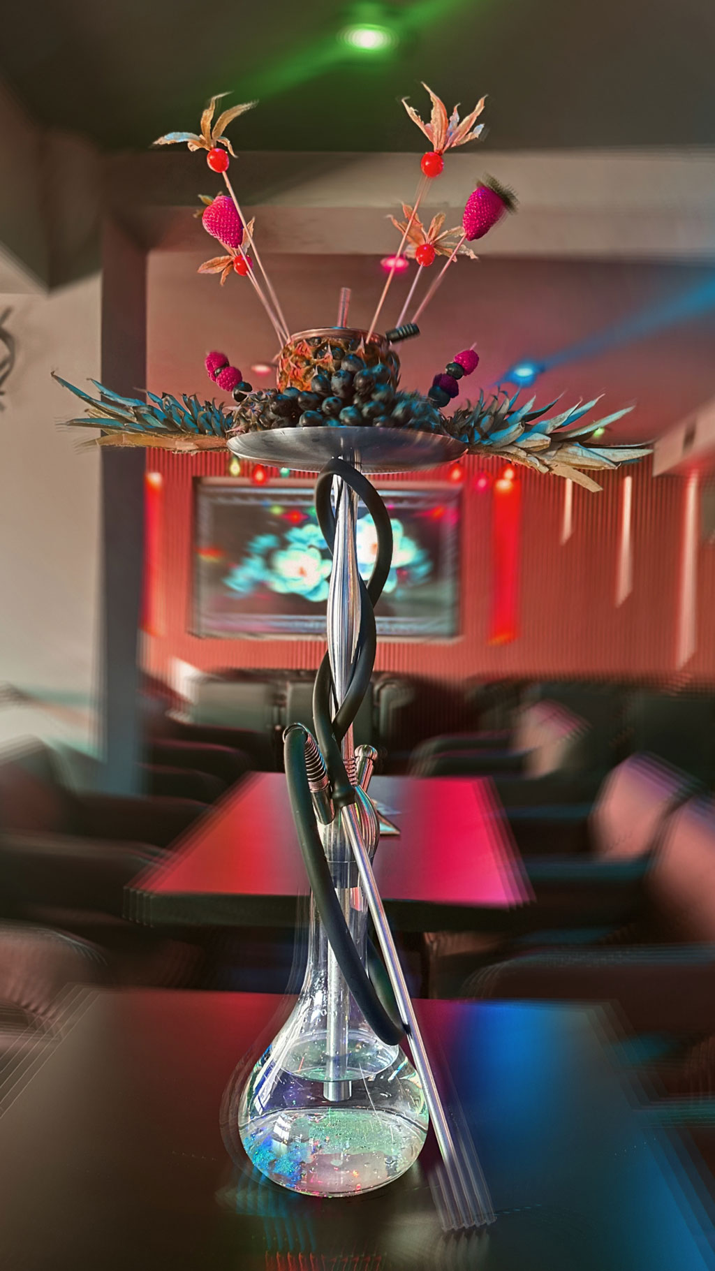 Shisha mit Dekoration aus Früchten und Blumen in einem hell erleuchteten, modernen Café.